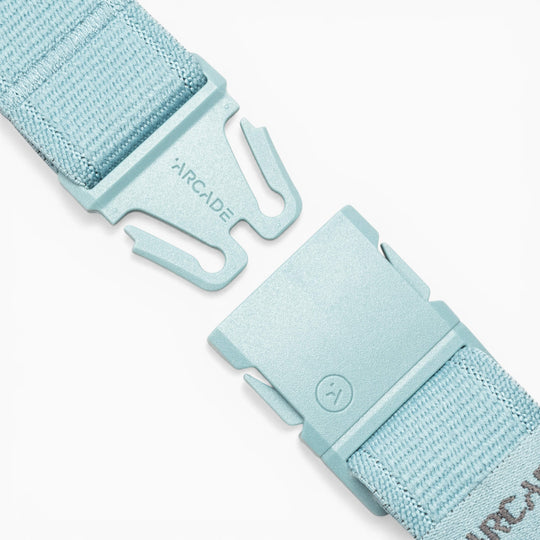 Close-up of the Atlas adventure belt by Arcade Belts in light blue, featuring a partially unfastened plastic A2 buckle engraved with the Arcade logo. Designed for easy adjustment, the woven fabric strap showcases Arcade Belts’ dedication to durable, comfortable performance stretch belts.
