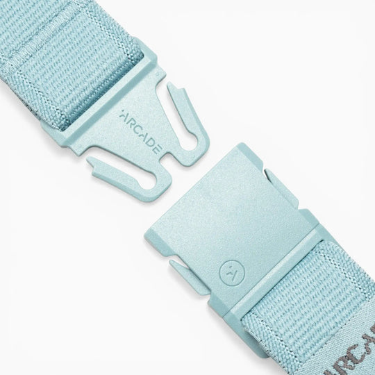Close-up of the Atlas adventure belt by Arcade Belts in light blue, featuring a partially unfastened plastic A2 buckle engraved with the Arcade logo. Designed for easy adjustment, the woven fabric strap showcases Arcade Belts’ dedication to durable, comfortable performance stretch belts.