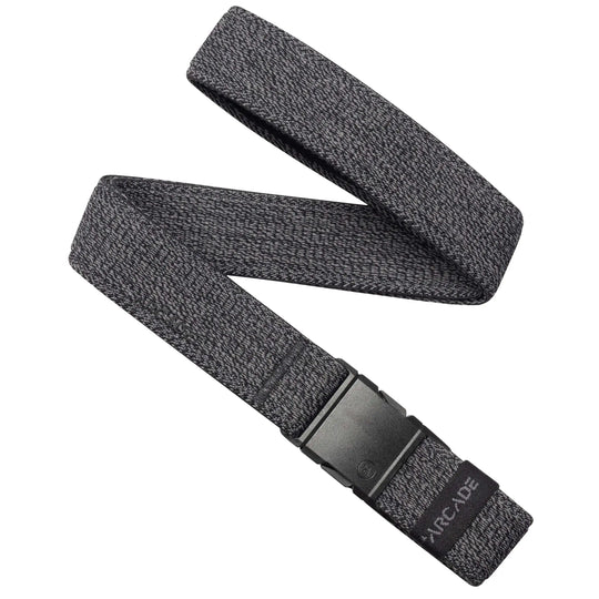The Atlas Slim Kit by Arcade Belts is a gray stretch webbing travel belt with a black low-profile buckle, partially coiled in an S shape. The buckle features a subtle design and ARCADE branding on one end.