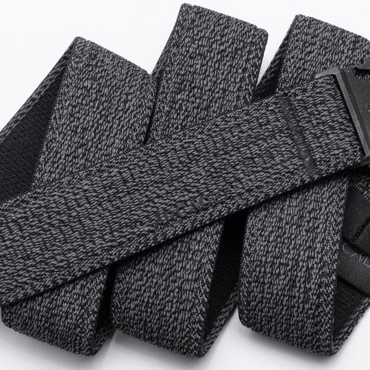 A close-up of the Atlas belt by Arcade Belts showcases its textured gray stretch webbing and black buckle. The elastic belt, looped on a white background, features the ARCADE branding subtly embossed on its surface.