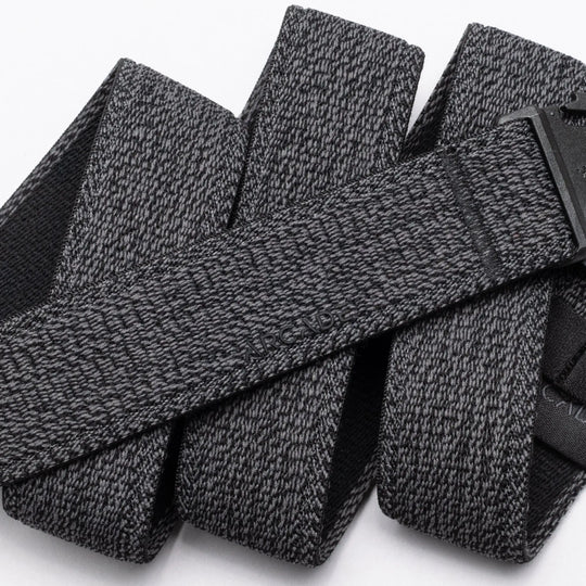 A close-up of the Atlas belt by Arcade Belts showcases its textured gray stretch webbing and black buckle. The elastic belt, looped on a white background, features the ARCADE branding subtly embossed on its surface.