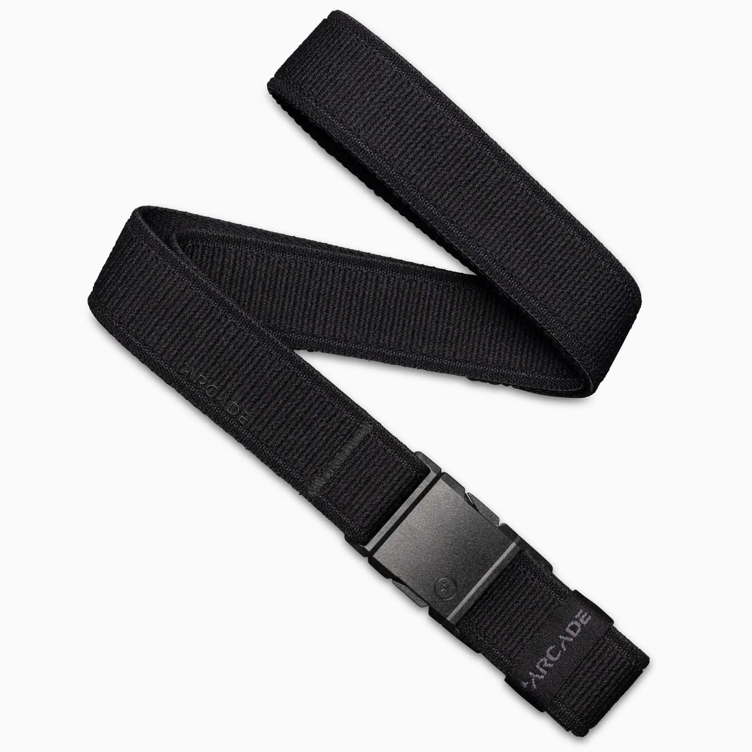 The Arcade Belts Atlas, a black low-profile belt made of stretch webbing with a plastic buckle, is shown coiled on a white background. ARCADE is visible near the buckle.