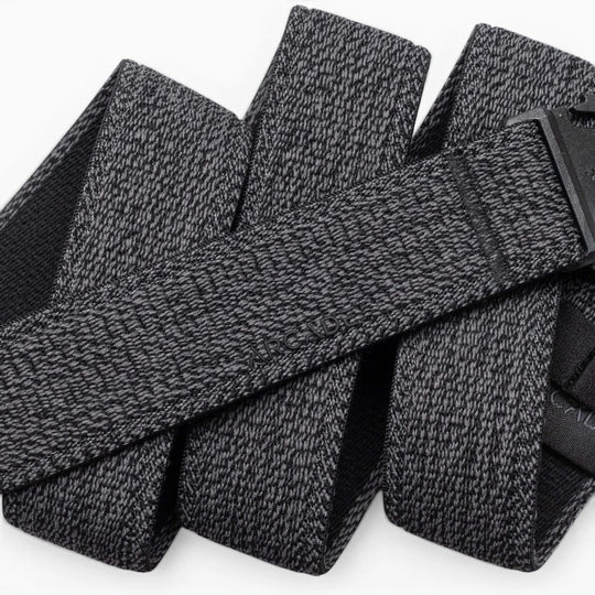 A close-up of the Atlas belt by Arcade Belts showcases its textured gray stretch webbing and black buckle. The elastic belt, looped on a white background, features the ARCADE branding subtly embossed on its surface.