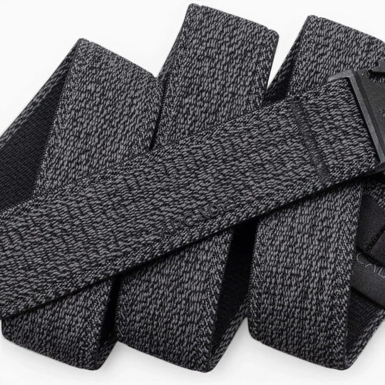A close-up of the Atlas belt by Arcade Belts showcases its textured gray stretch webbing and black buckle. The elastic belt, looped on a white background, features the ARCADE branding subtly embossed on its surface.