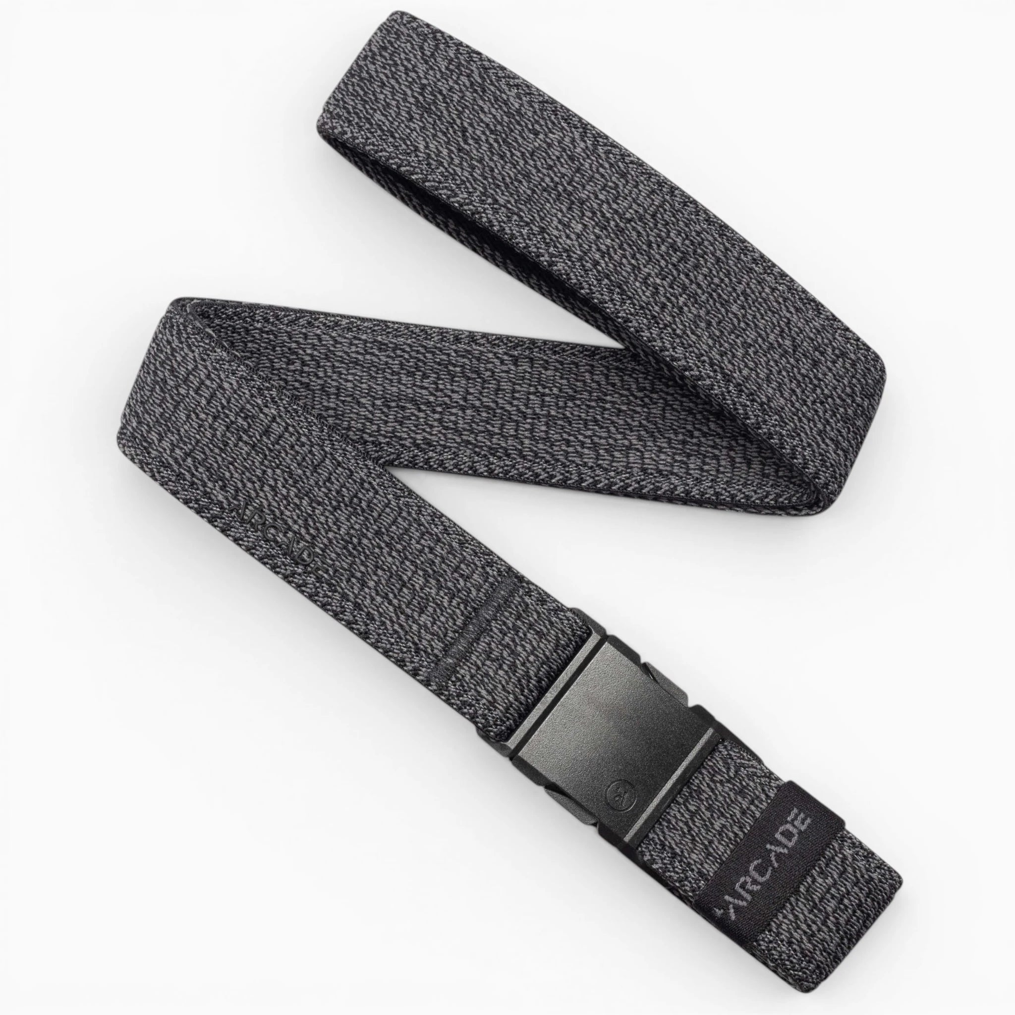 The Atlas by Arcade Belts is a gray woven elastic stretch belt with a subtle pattern and a black plastic buckle. Partially coiled on a white background, the ARCADE logo appears near the buckle.
