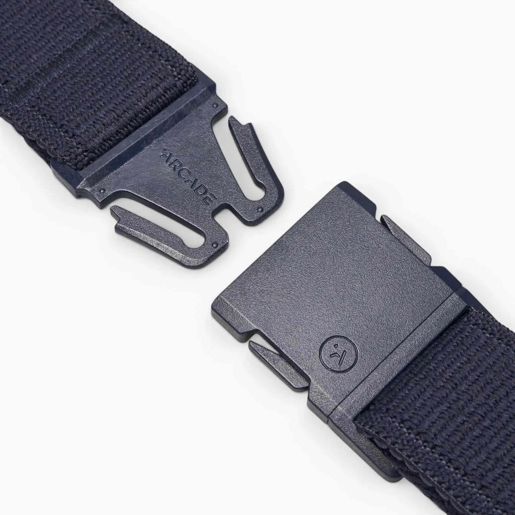 A close-up of a black Atlas belt by Arcade Belts with a plastic buckle, showing the separated ends—one featuring ARCADE, the other a small sad face icon—highlighting its stretch webbing design on a light background.