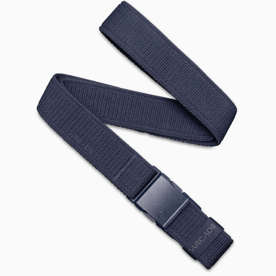 The Atlas belt by Arcade Belts is navy blue with a black plastic buckle featuring ARCADE embossed near it. This low-profile, elastic stretch belt ensures comfort and is displayed on a white background.