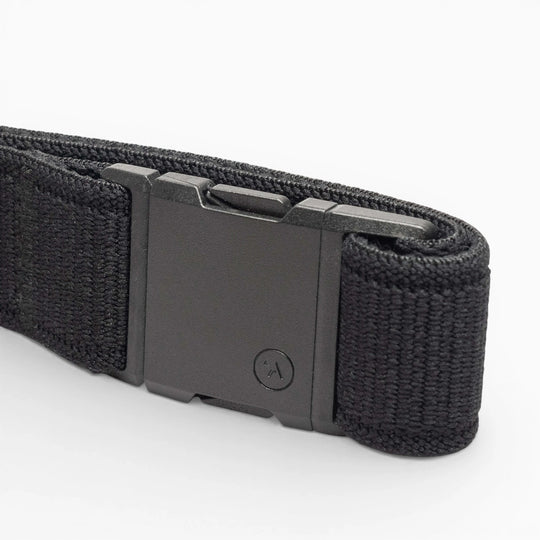 The Atlas by Arcade Belts is a black woven low-profile belt with a matte black rectangular buckle, neatly coiled on a white background—ideal for travel and daily wear.