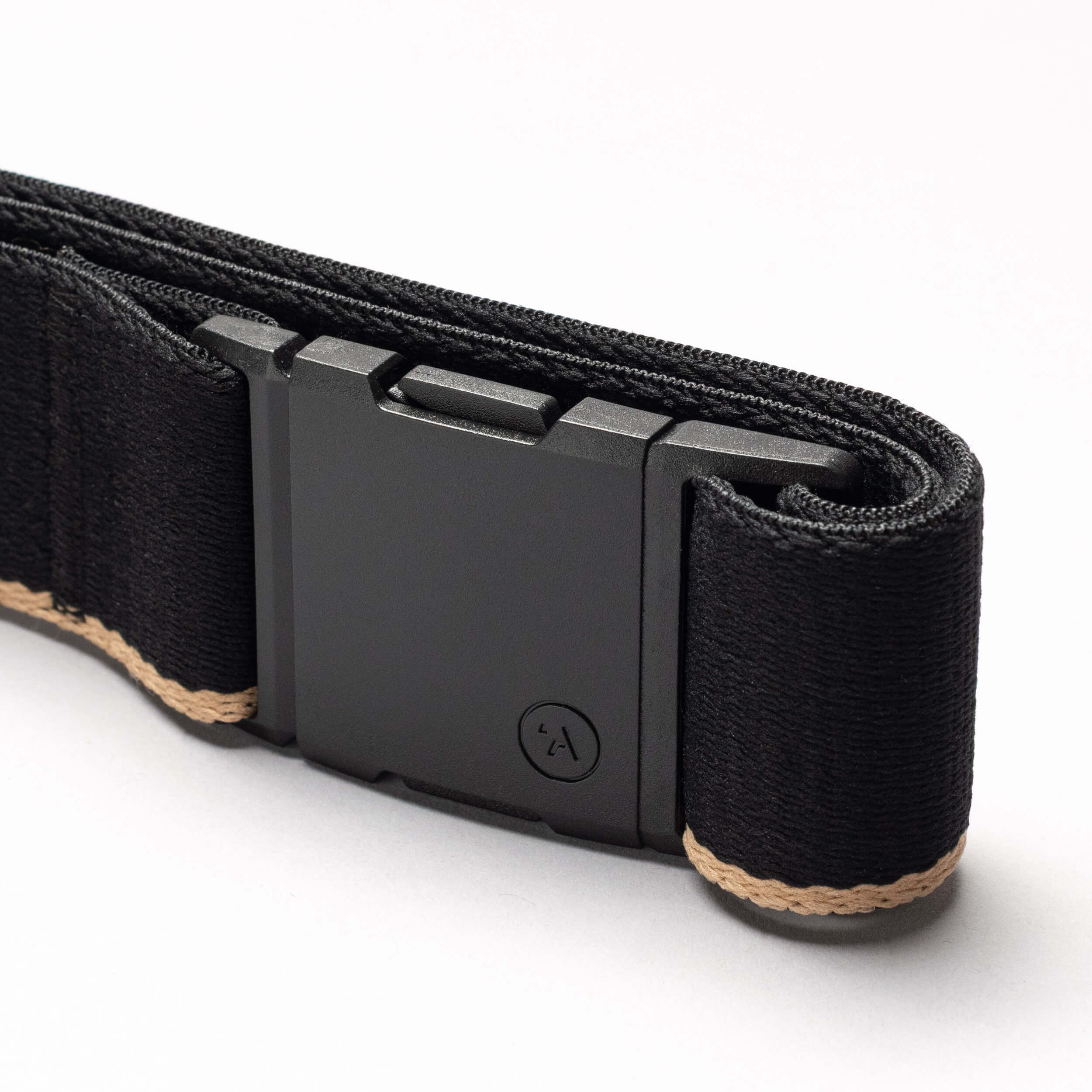 A close-up of the Arcade Belts Blackwood belt showcases its rectangular matte black A2 buckle and tan edge stitching, neatly rolled on a white surface.