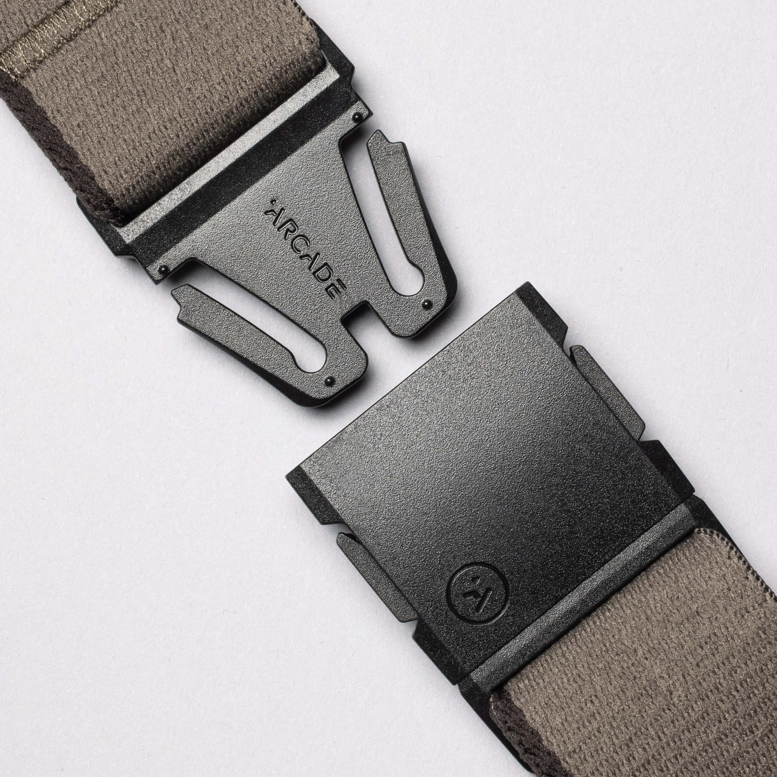 Close-up of a Blackwood A2 buckle in black metal with Arcade Belts branding on a taupe fabric strap, shown unfastened against a light background—ideal for adventurous explorers.