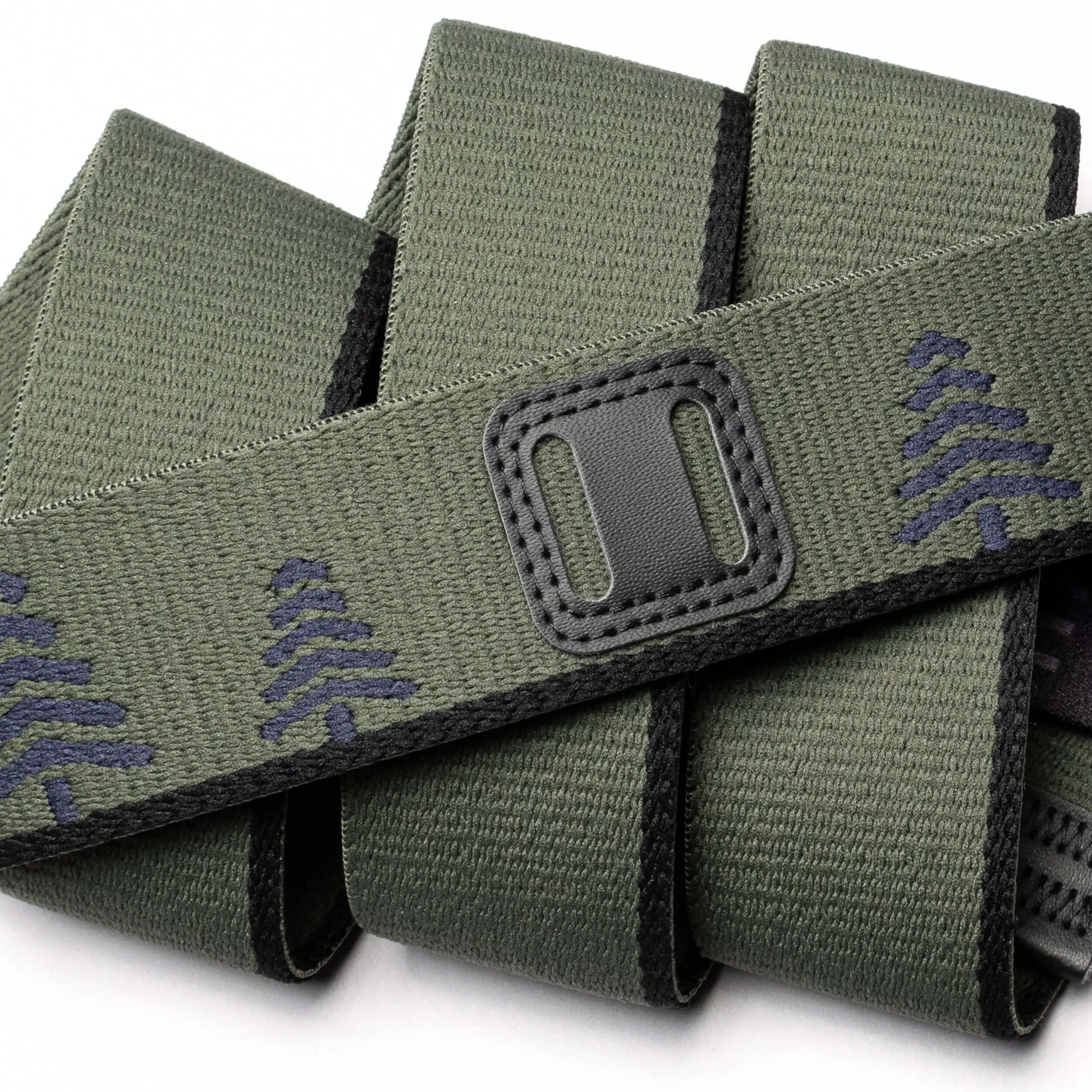 A close-up of the Blackwood belt by Arcade Belts: green fabric with black edging, decorated with navy blue tree patterns and a classic refreshed rectangular black patch featuring two horizontal openings.