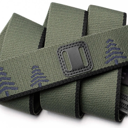 A close-up of the Blackwood belt by Arcade Belts: green fabric with black edging, decorated with navy blue tree patterns and a classic refreshed rectangular black patch featuring two horizontal openings.