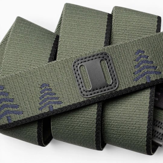 A close-up of the Blackwood belt by Arcade Belts: green fabric with black edging, decorated with navy blue tree patterns and a classic refreshed rectangular black patch featuring two horizontal openings.