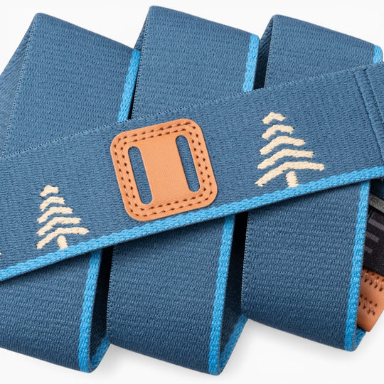 A stylish coiled belt from Arcade Belts, the Blackwood, features blue fabric adorned with tan tree patterns and a tan leather A2 buckle bordered in light blue—a subtle homage to the Blackwood design.