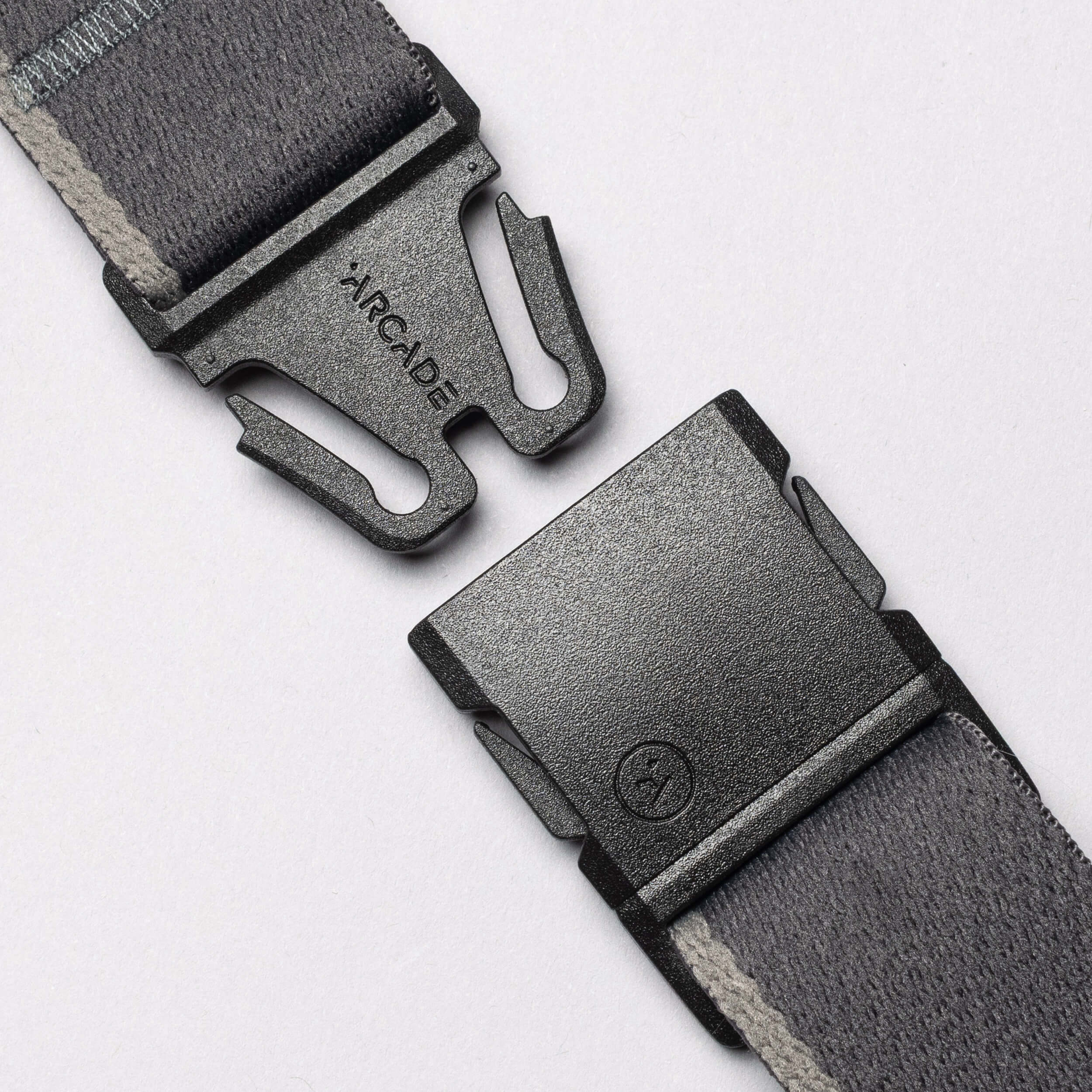 A close-up of the Arcade Belts Blackwood—an unfastened gray fabric belt with an A2 buckle—perfect for explorers, displayed on a light background.