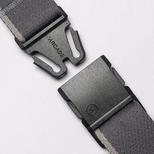 A close-up of the Arcade Belts Blackwood—an unfastened gray fabric belt with an A2 buckle—perfect for explorers, displayed on a light background.