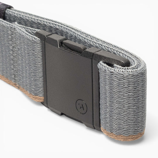 A close-up of a gray fabric strap with a black plastic buckle, featuring the signature A2 buckle from Arcade Belts. The strap, named Blackwood, displays brown edge stitching, while the buckle is adorned with a small circular logo for an iconic Arcade touch.