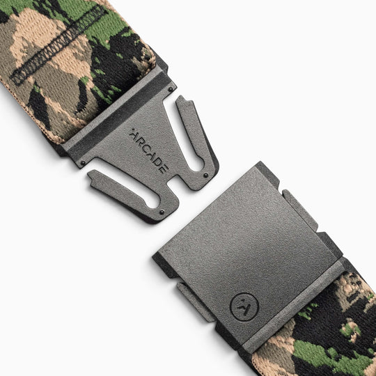 A close-up of a camouflage-patterned fabric belt from the Island Collection by Arcade Belts, featuring a partially open black metal buckle embossed with the ARCADE logo, captures the spirit of Aloha against a crisp white background.