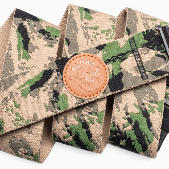 Introducing the Island Collection by Arcade Belts: this camouflage-patterned fabric belt showcases a round brown leather patch embossed with “ALOHA” and a shaka hand symbol, capturing the true spirit of Hawaii. Part of our exclusive Hawaiian series, this stylish accessory is finished with a sleek black buckle and presented in overlapping folds.