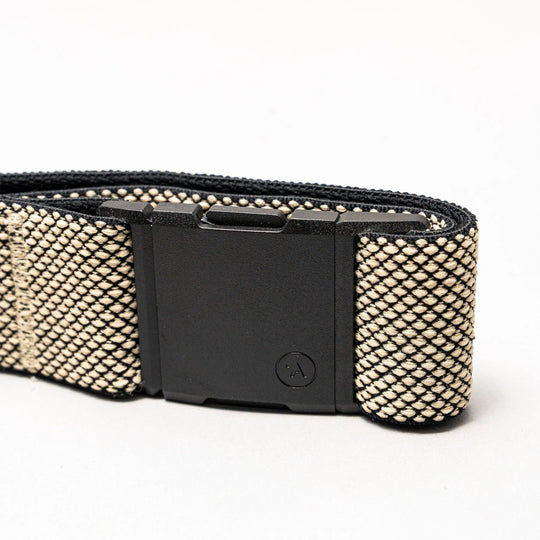A close-up of the Arcade Belts Carry, a woven beige and black belt with a matte black rectangular A2 buckle and performance stretch webbing, displayed on a plain white background.