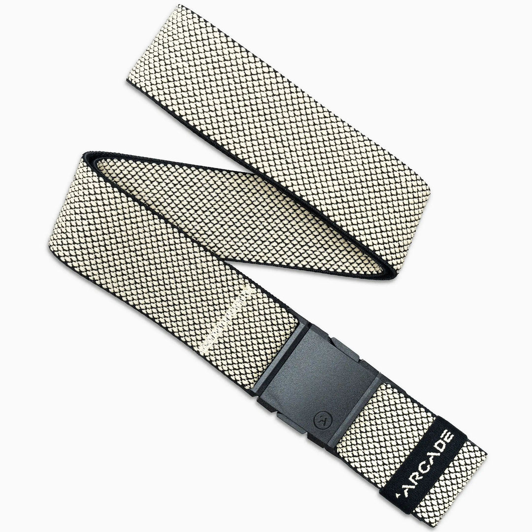 The Arcade Belts Carry is a woven fabric belt with a black rectangular A2 buckle, featuring cream and black geometric performance stretch webbing and ARCADE printed near the end. It is displayed diagonally on a white background.