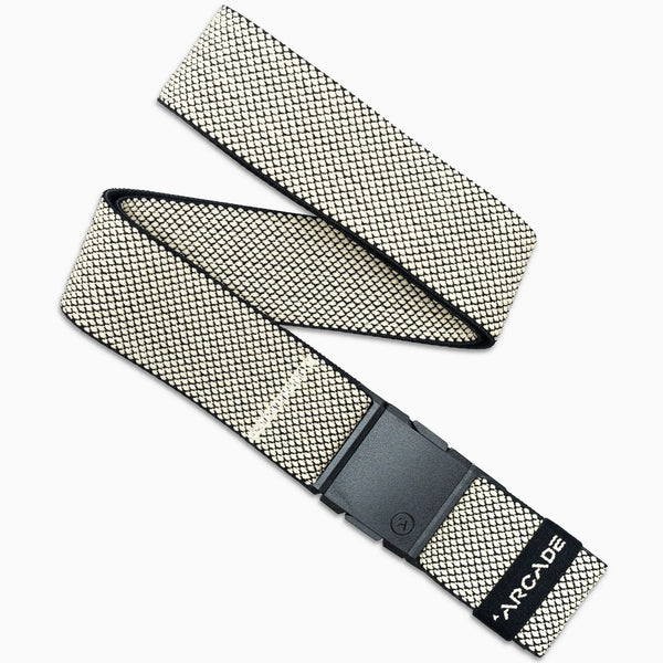 The Arcade Belts Carry is a woven fabric belt with a black rectangular A2 buckle, featuring cream and black geometric performance stretch webbing and ARCADE printed near the end. It is displayed diagonally on a white background.