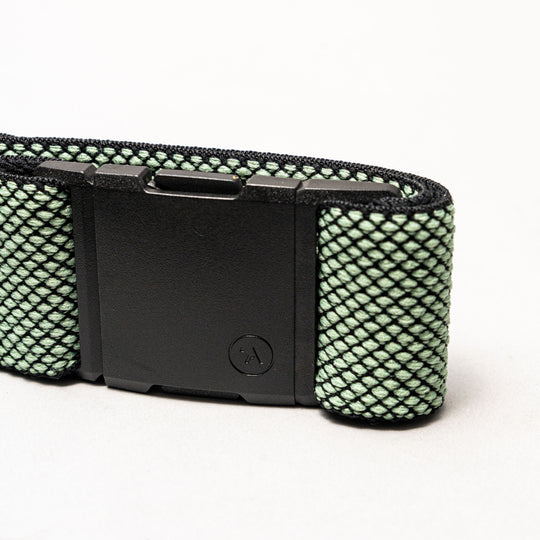 A close-up of the Arcade Belts Carry belt, featuring an A2 buckle and a green textured strap with a unique weave and black net-like pattern, displayed against a plain white background.
