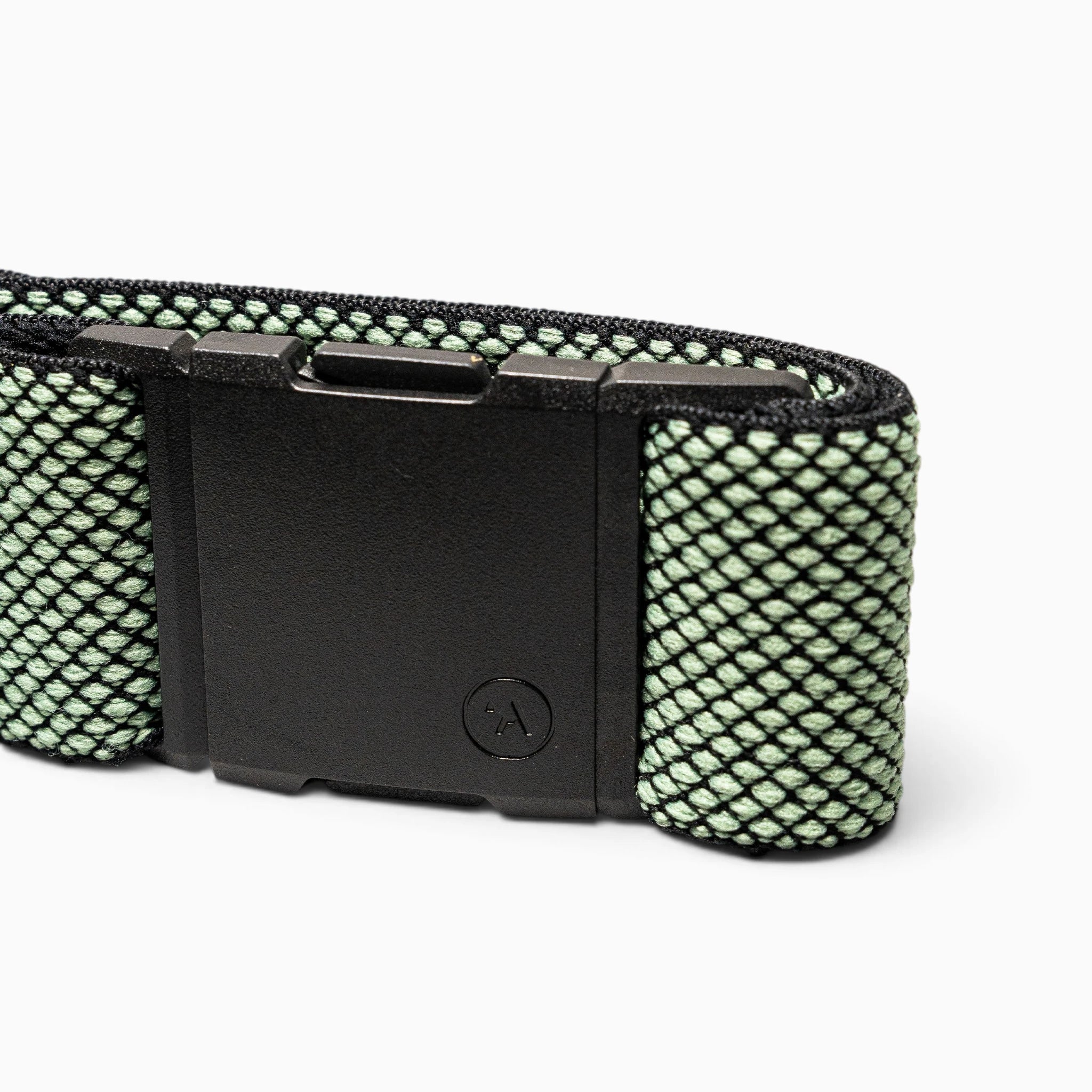 A close-up of the black A2 buckle on the Carry belt by Arcade Belts, attached to a green and black mesh-patterned performance stretch webbing strap, displayed against a white background.