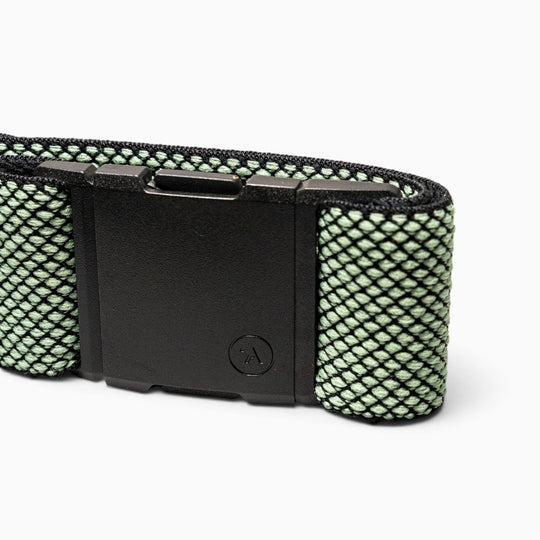 A close-up of the black A2 buckle on the Carry belt by Arcade Belts, attached to a green and black mesh-patterned performance stretch webbing strap, displayed against a white background.