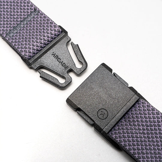 A close-up of the Carry belt by Arcade Belts, featuring an A2 buckle on a purple and white unique weave strap, shown unfastened against a light gray background.