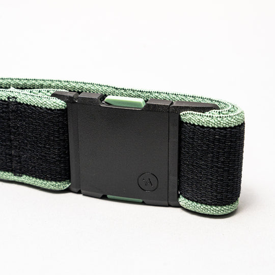 A close-up of the black and green Carto Low Profile Belt by Arcade Belts, made from stretch webbing with a rectangular black plastic buckle, displayed against a plain white background.