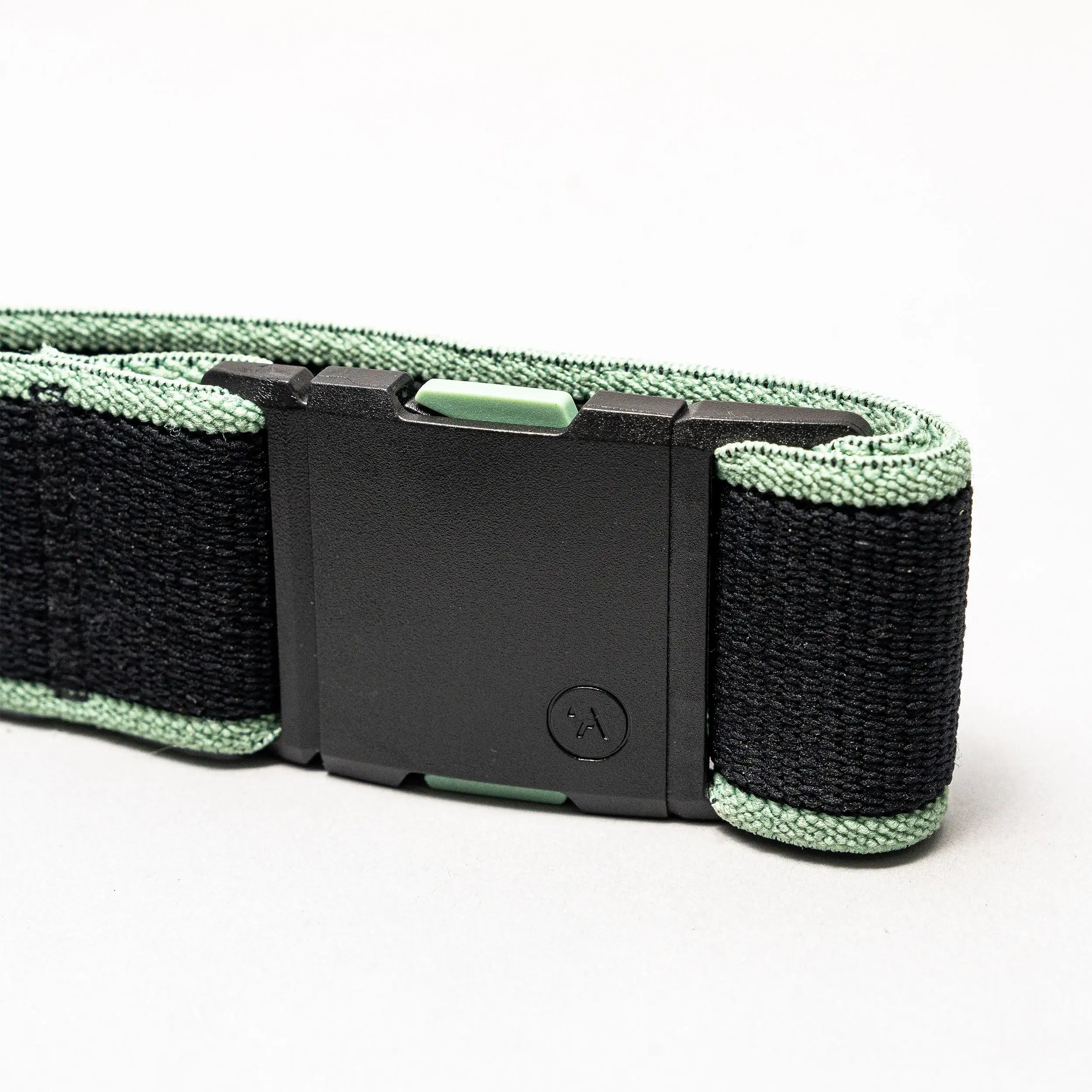 A close-up of the black and green Carto Low Profile Belt by Arcade Belts, made from stretch webbing with a rectangular black plastic buckle, displayed against a plain white background.