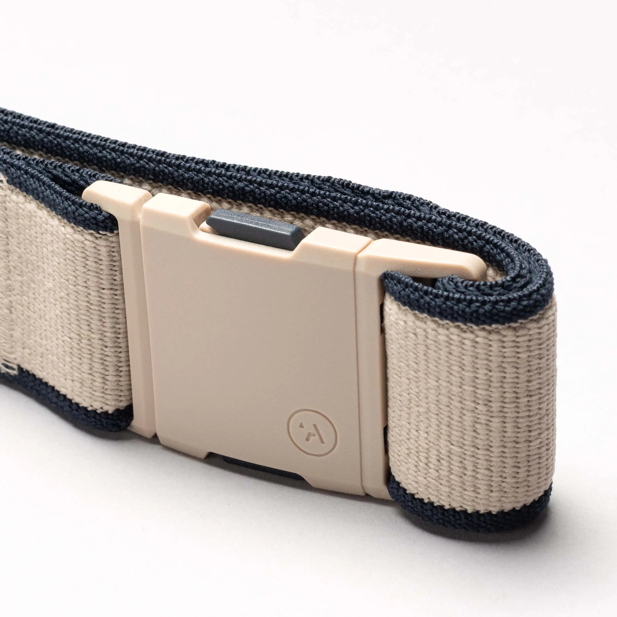 A close-up of the beige and navy blue Carto belt from Arcade Belts, featuring a rectangular light tan plastic buckle, set against a plain white background.