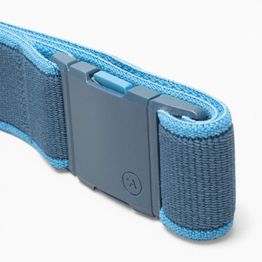 Close-up of the Arcade Belts Carto performance stretch belt in blue, featuring a rectangular gray plastic buckle with a small circular logo and a blue sliding release button—crafted for adventure in every detail.