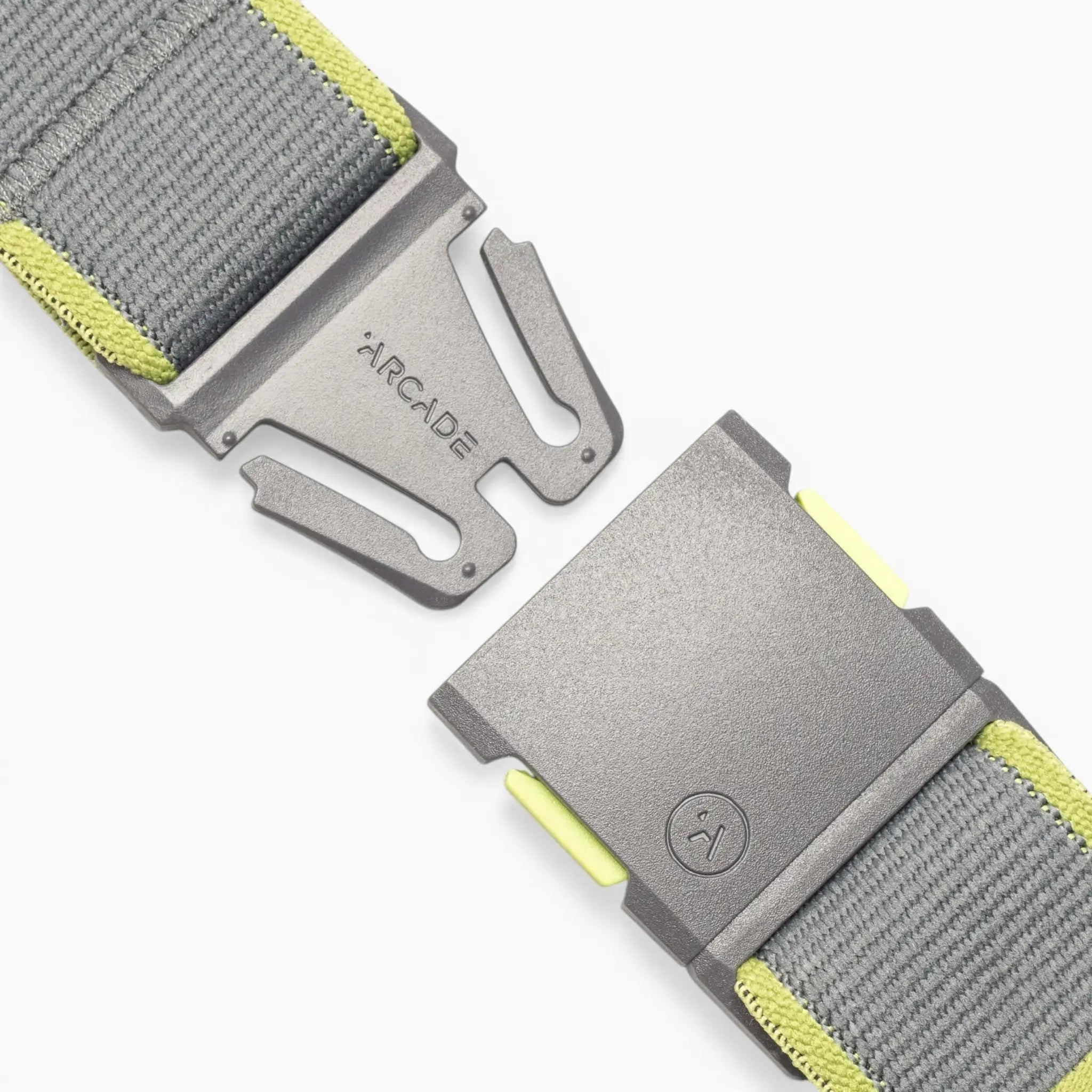 A close-up of a gray and yellow Carto performance stretch belt by Arcade Belts, featuring a metal buckle engraved with the ARCADE name and a simple smiley face logo. Designed for adventure, the belt’s detailed stitching and secure clasp are prominently displayed, highlighting the high-quality construction that sets Arcade Belts apart.
