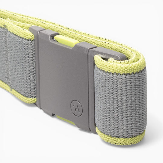 A close-up of a gray and yellow Arcade Belts Carto performance stretch belt strap with a rectangular plastic buckle, featuring a small circular logo—perfect for adventure.