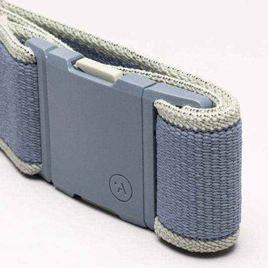 A close-up of the Carto by Arcade Belts—a gray and light blue performance stretch belt wristband with a rectangular plastic buckle and a small circular logo—shown on a plain background to highlight its adventure-ready design.