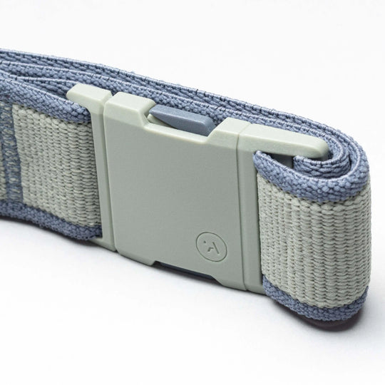 A close-up of a light gray plastic buckle on a folded blue woven strap highlights the durability of the Carto performance stretch belt by Arcade Belts, shown against a plain white background—ideal for any adventure.