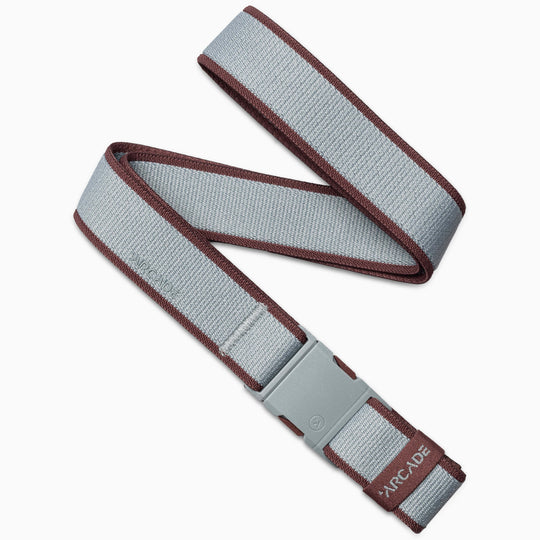A gray Carto belt by Arcade Belts with maroon edges, a gray plastic buckle, and ARCADE branding at the end. Made from stretch webbing and shown loosely folded.