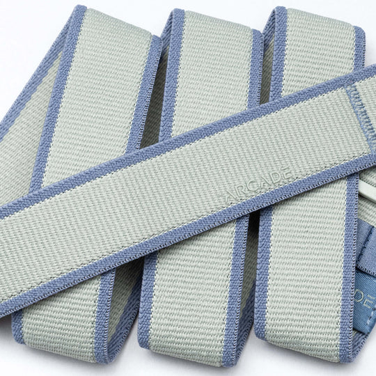 A close-up of folded grey and light blue Carto resistance bands by Arcade Belts, featuring textured material, reinforced edges, and a subtly embossed brand name that reflects the quality of their performance stretch belts.