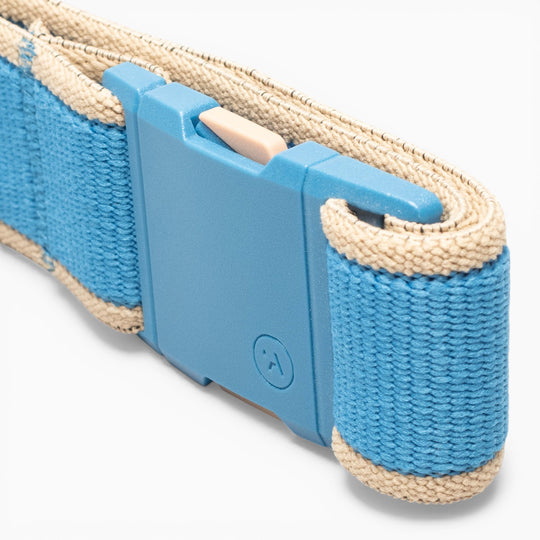 A close-up of a blue fabric strap with beige edges and a plastic buckle highlights the simple locking mechanism—perfect for adventure, the Carto performance stretch belt from Arcade Belts delivers both comfort and security.