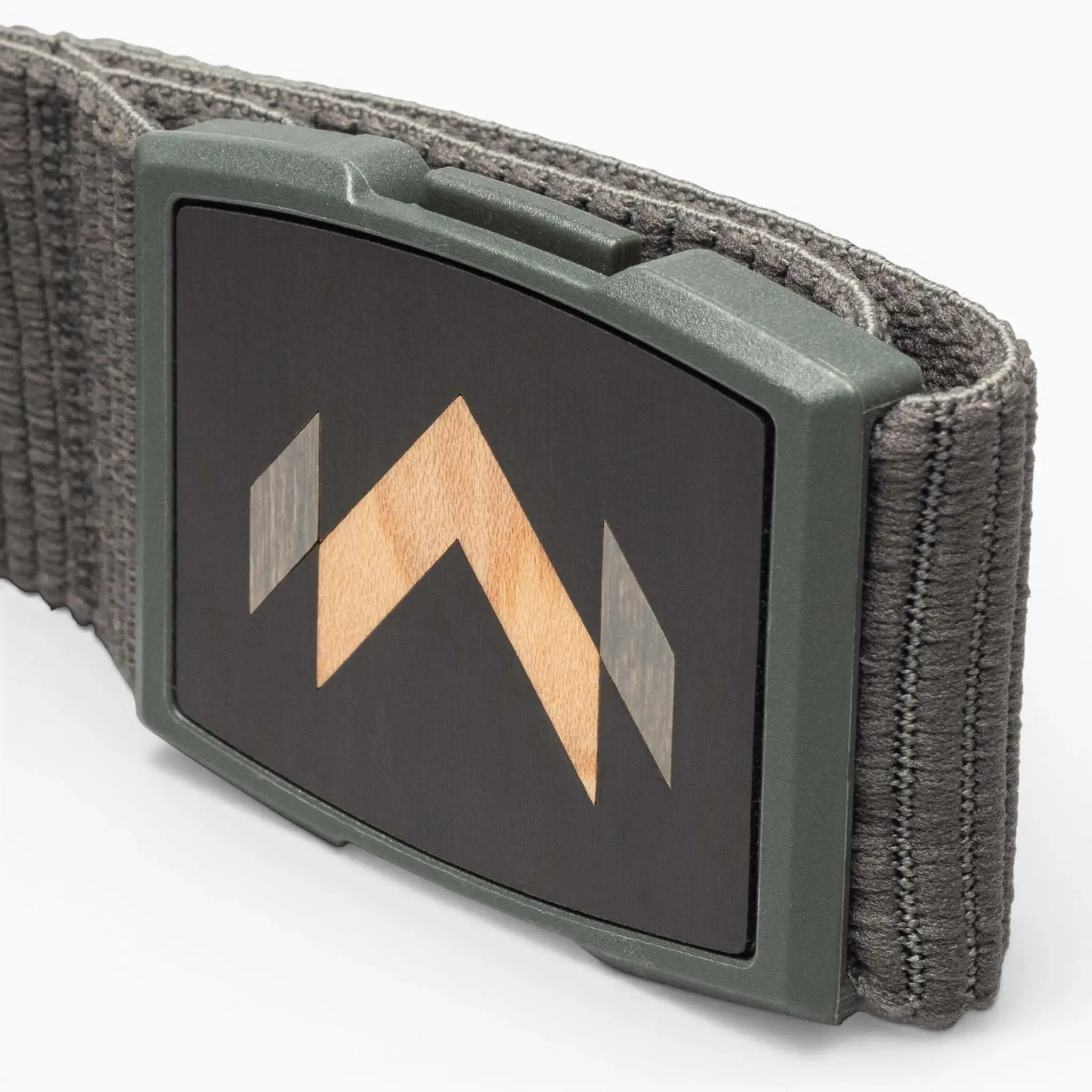 A close-up of the Arcade Belts Carver: a gray stretch belt with a rectangular buckle featuring a black face and geometric wood inlay with light and dark wood tones—a signature Carver detail.