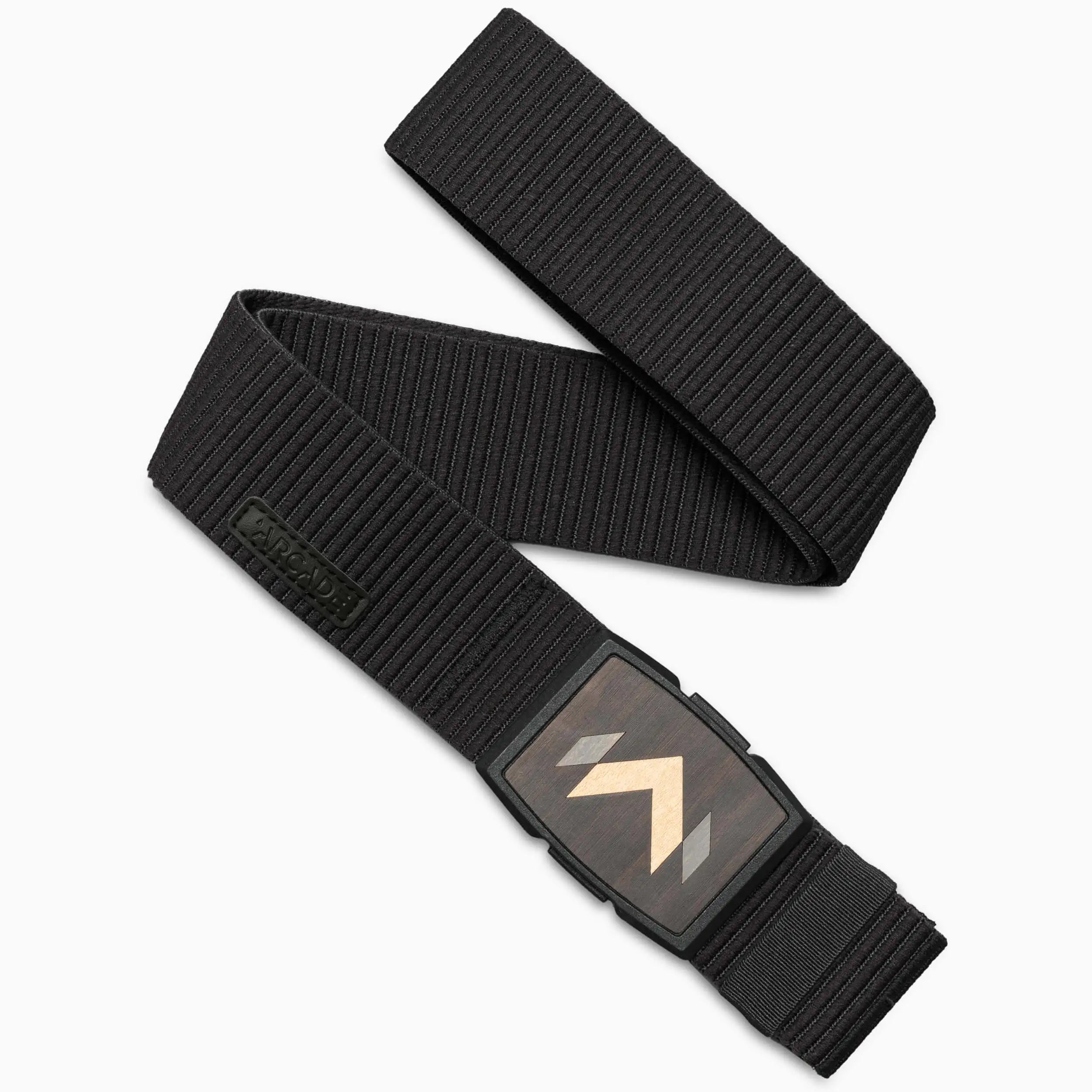 The Arcade Belts Carver is a black, textured stretch belt with a wood-like rectangular buckle and light chevron arrow pattern, styled in a loose, overlapping loop for an effortlessly cool look.