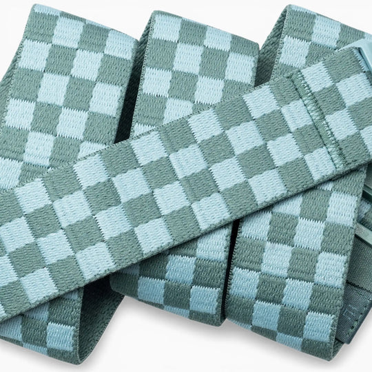 A close-up of the Check belts by Arcade Belts, featuring light blue and teal woven bands in a checkerboard pattern, stacked and overlapping—crafted with performance stretch for flexibility made for movement.