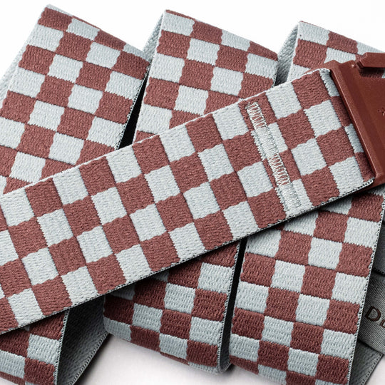 A close-up of the Arcade Belts Check belt shows its brown and light blue checkerboard woven fabric and brown buckle—a stylish Stretch Webbing option.
