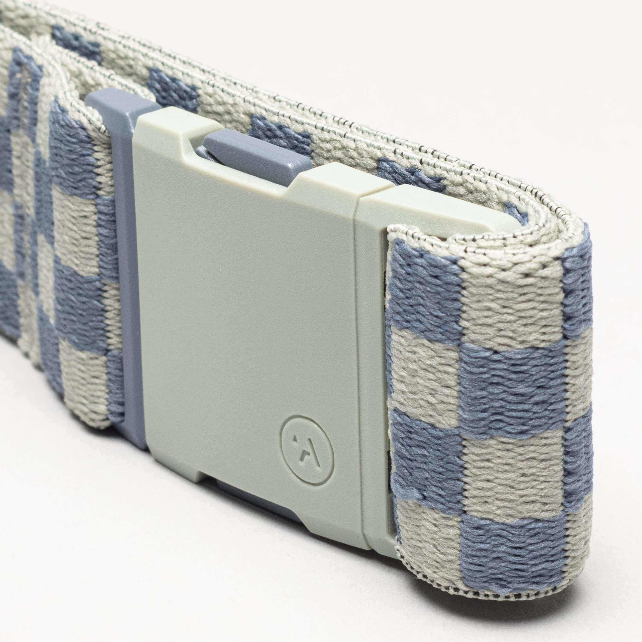 A close-up of the Arcade Belts Check, a fabric belt with a blue and gray checkerboard pattern, matte light gray rectangular buckle, and performance stretch for comfort, shown against a plain light background.