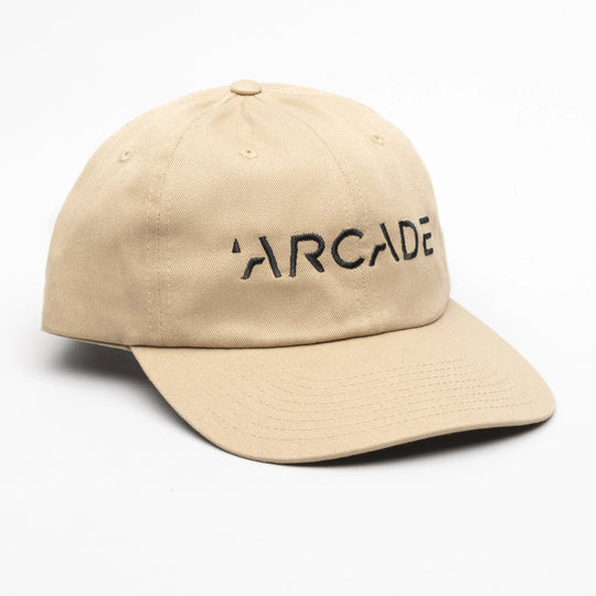 The Arcade Dad Hat by Arcade Belts is a beige baseball cap featuring “ARCADE” in black capital letters on the front, inspired by their iconic low profile belt style, shown on a white background.