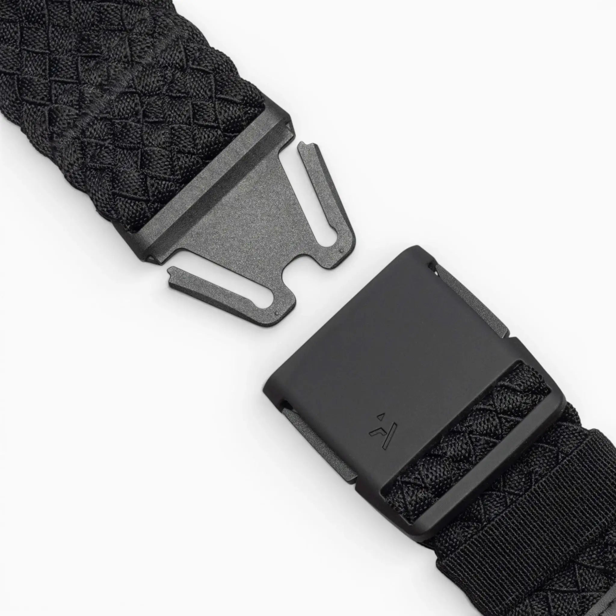 Close-up of the Arcade Belts Futureweave: a black woven belt with a matte black metal buckle, shown partially unclasped against a white background. It features a textured crisscross pattern for a comfortable fit.