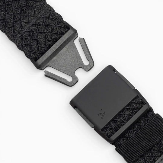Close-up of the Arcade Belts Futureweave: a black woven belt with a matte black metal buckle, shown partially unclasped against a white background. It features a textured crisscross pattern for a comfortable fit.
