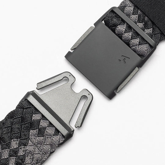 Close-up of the Arcade Belts Futureweave, a black and gray woven webbing belt with a rectangular metal buckle, shown with its two clasped ends separated on a white background.